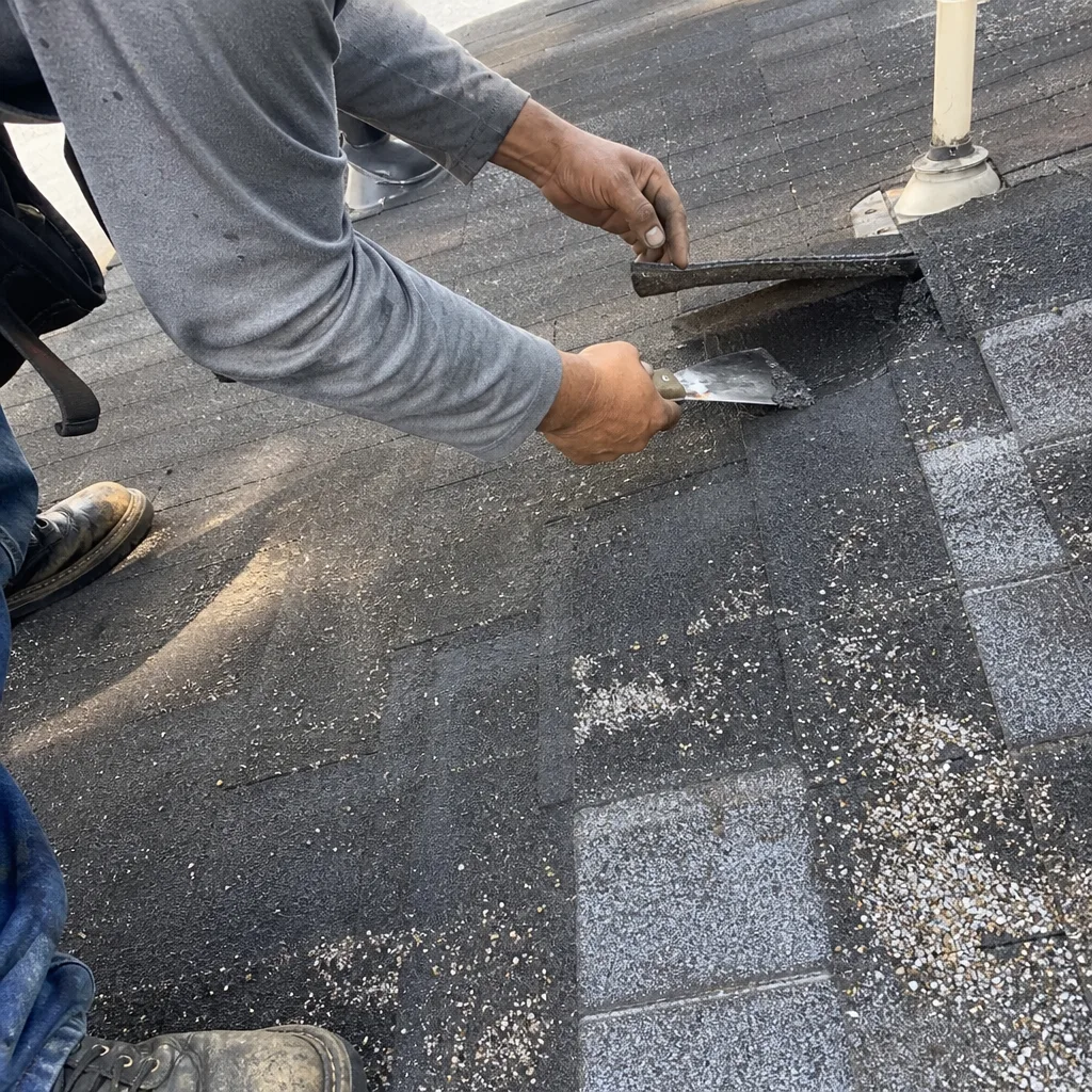 Professional roofer repairing damaged asphalt shingles on a roof